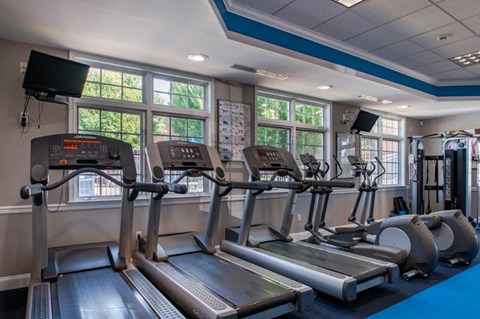 a gym with cardio equipment and windows