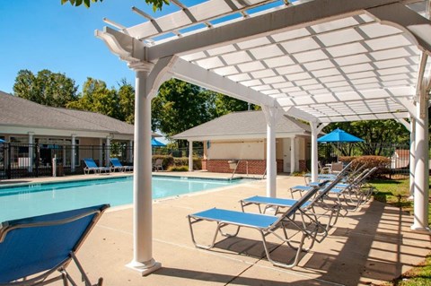 a swimming pool with chairs and a pool shade