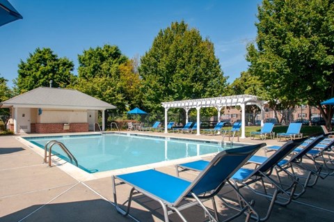 a swimming pool with blue chairs and a poolside pavilion