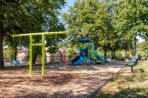 a playground with a blue and green slide in a park