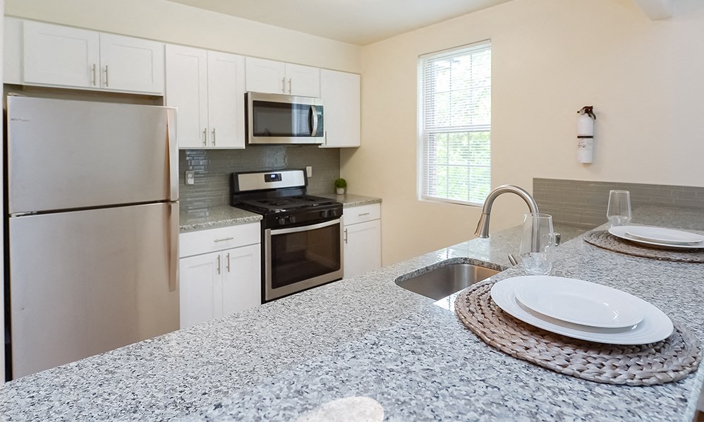 an updated kitchen with stainless steel appliances and granite counter tops