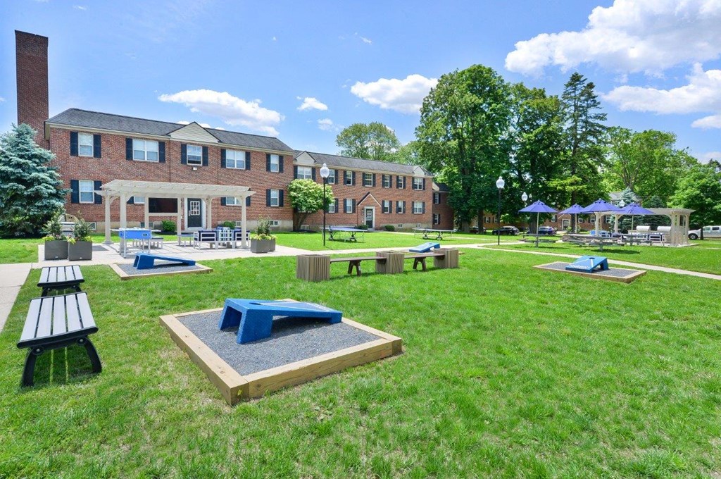a park with picnic tables and benches in front of a brick building