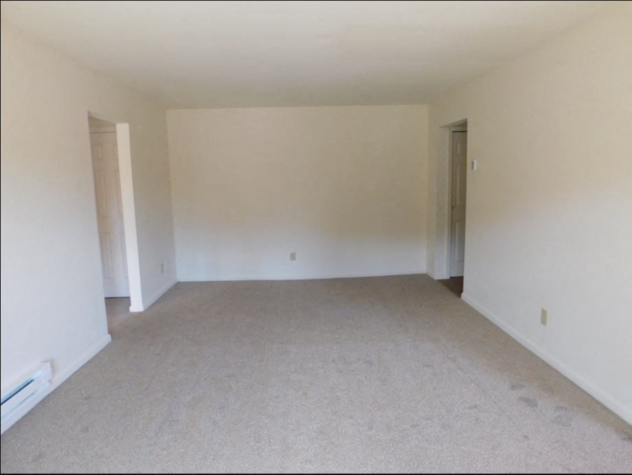 an empty living room with white walls and carpet