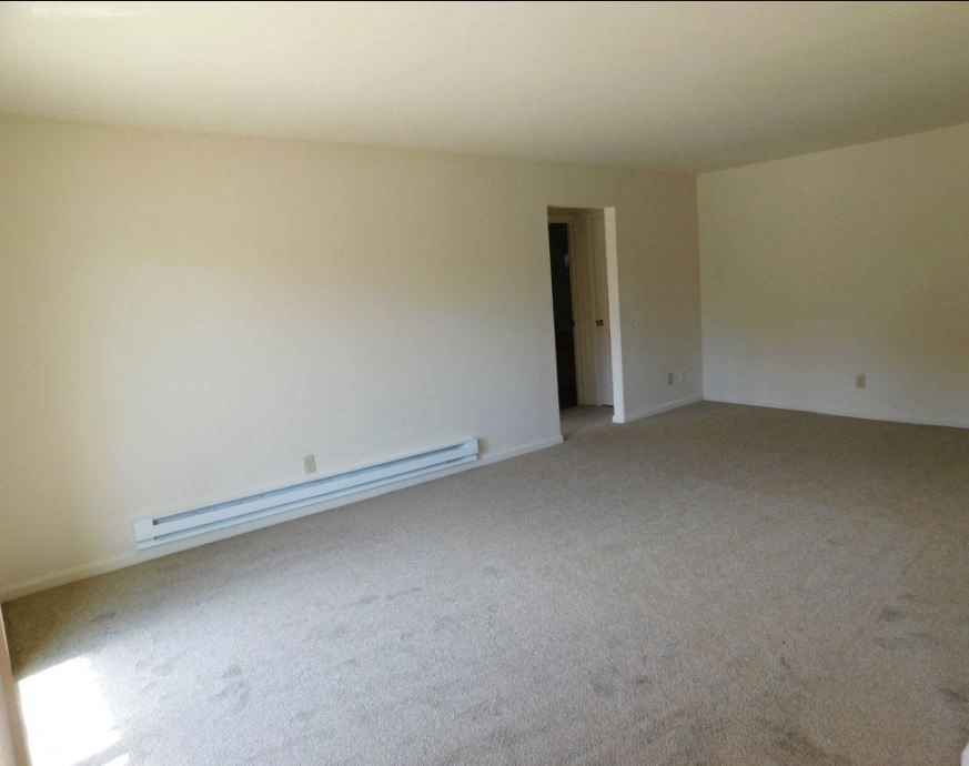 an empty living room with white walls and carpet