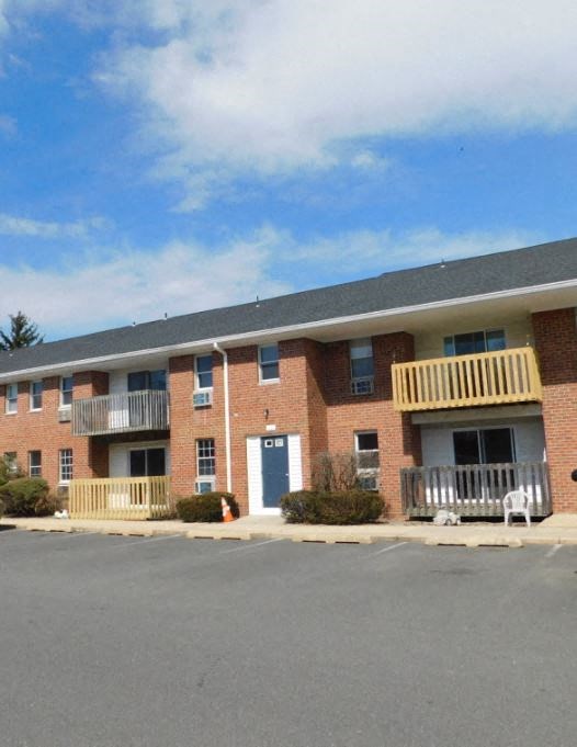a red brick apartment building with a porch and a blue sky