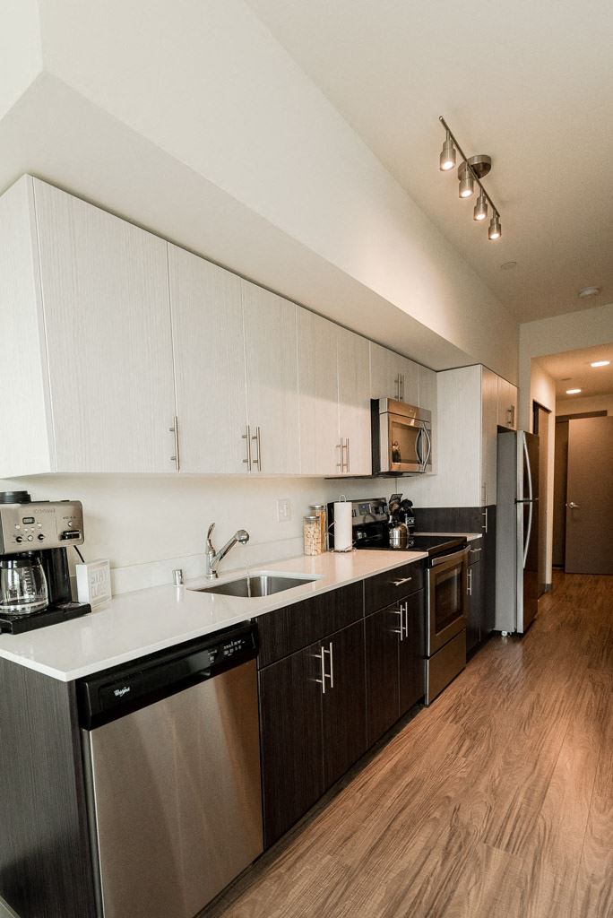 Apartments for Rent Seattle, WA - Apartment Entryway to Kitchen with Stainless Appliances, Modern Cabinetry, and Hardwood Flooring - Photo Gallery 1
