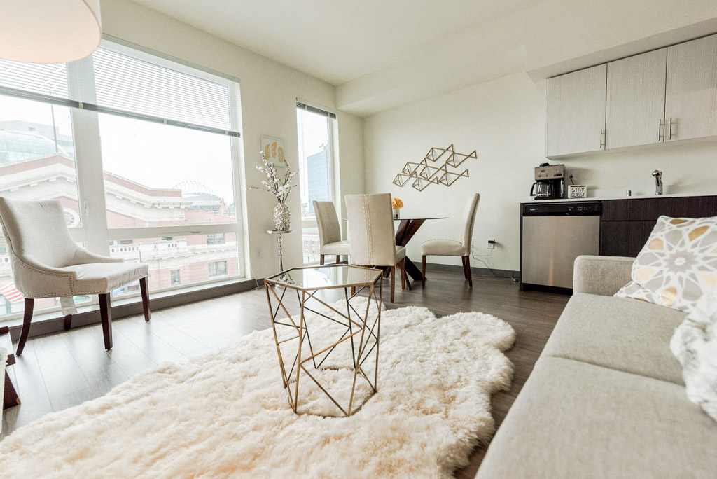 Apartments in Seattle, WA - Icon Apartments Modern Living Room Next to Kitchen with Hardwood Flooring and Natural Light
