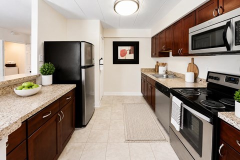 A kitchen with black appliances and brown cabinets.