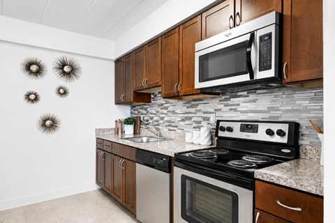 A kitchen with a black and white stove and a black microwave above it.
