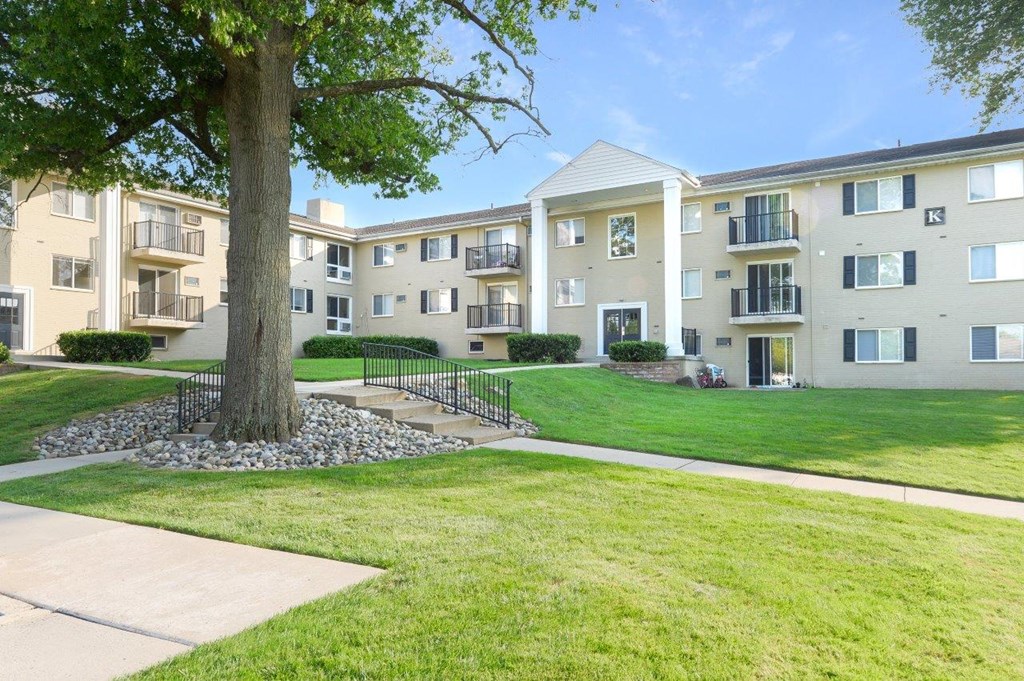 an exterior view of an apartment building with grass and a tree