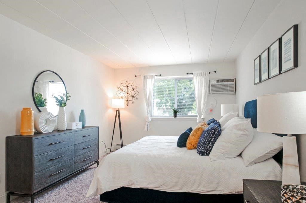 a bedroom with a bed and a dresser and a window