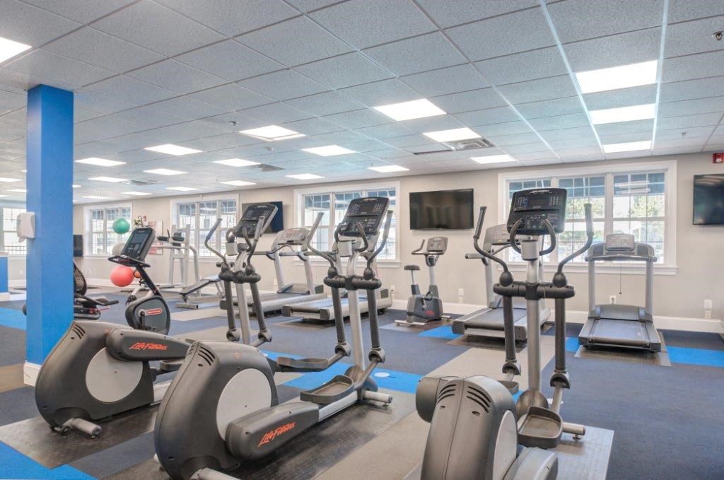 a gym with various exercise bikes and a television