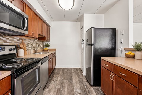 A kitchen with a black fridge and wooden cabinets.