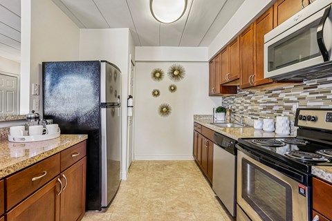 A kitchen with a black fridge and a black stove top oven.