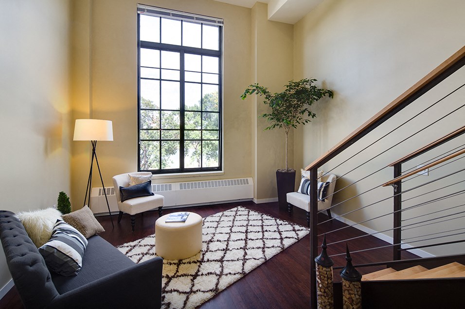 a living room with a staircase and a large window