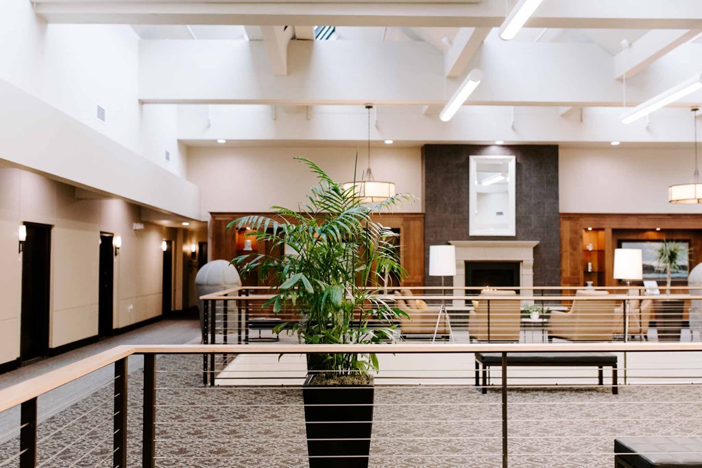 a large lobby with a table and chairs and a plant