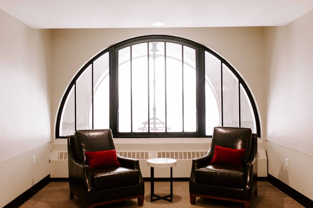 two leather chairs and a table in front of a large window