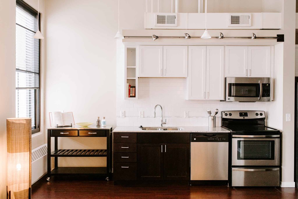 a kitchen with white cabinets and black appliances and a window