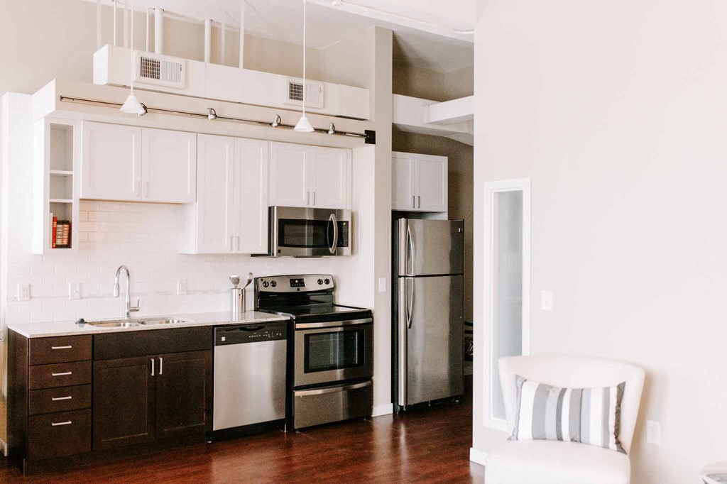 a kitchen with white cabinets and black appliances and a white chair