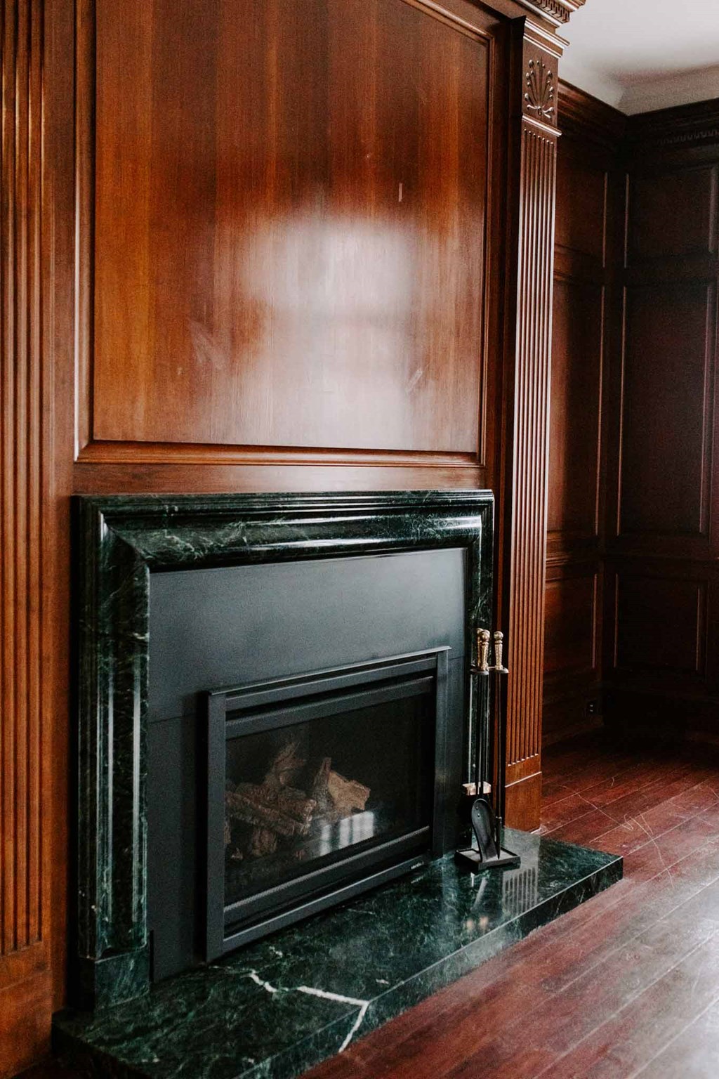 a fireplace in a wood paneled room with a wood floor