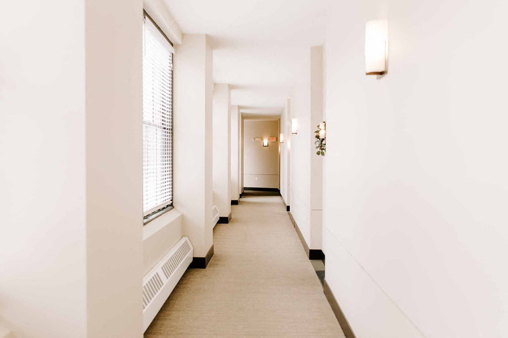 a long hallway with white walls and windows and a white carpet