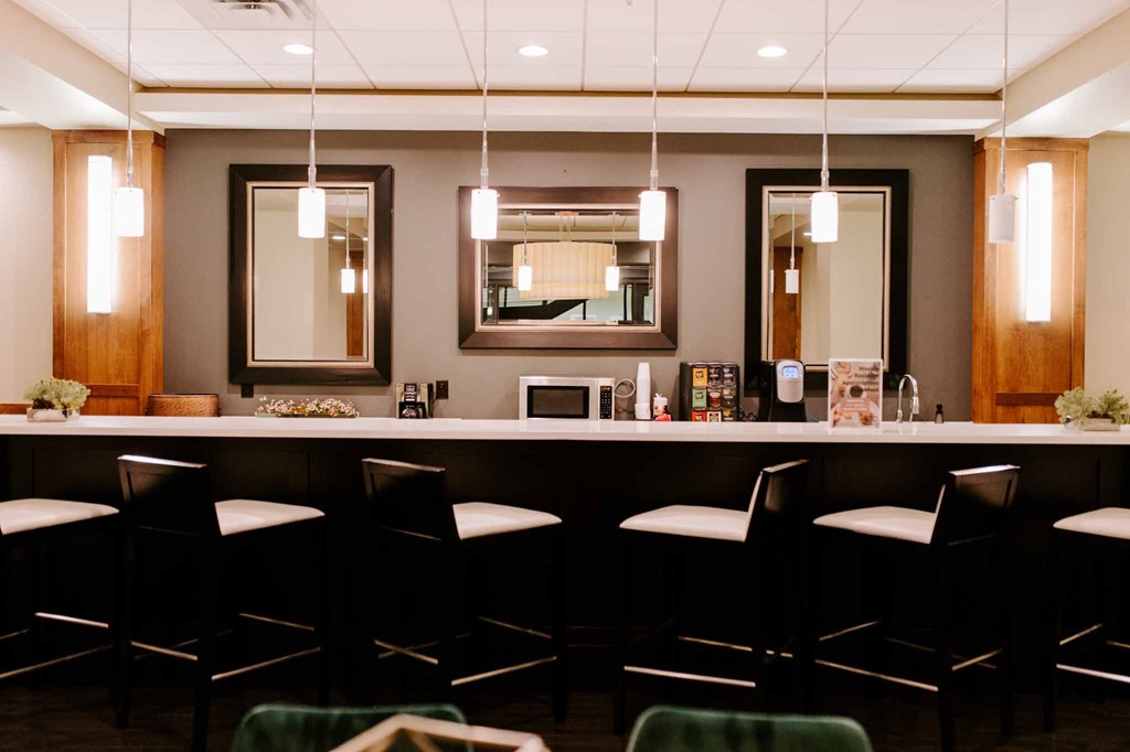 a bar with chairs and a mirror in a room