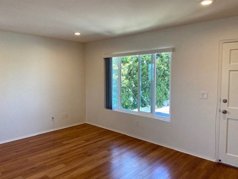 an empty living room with a large window and wooden floors