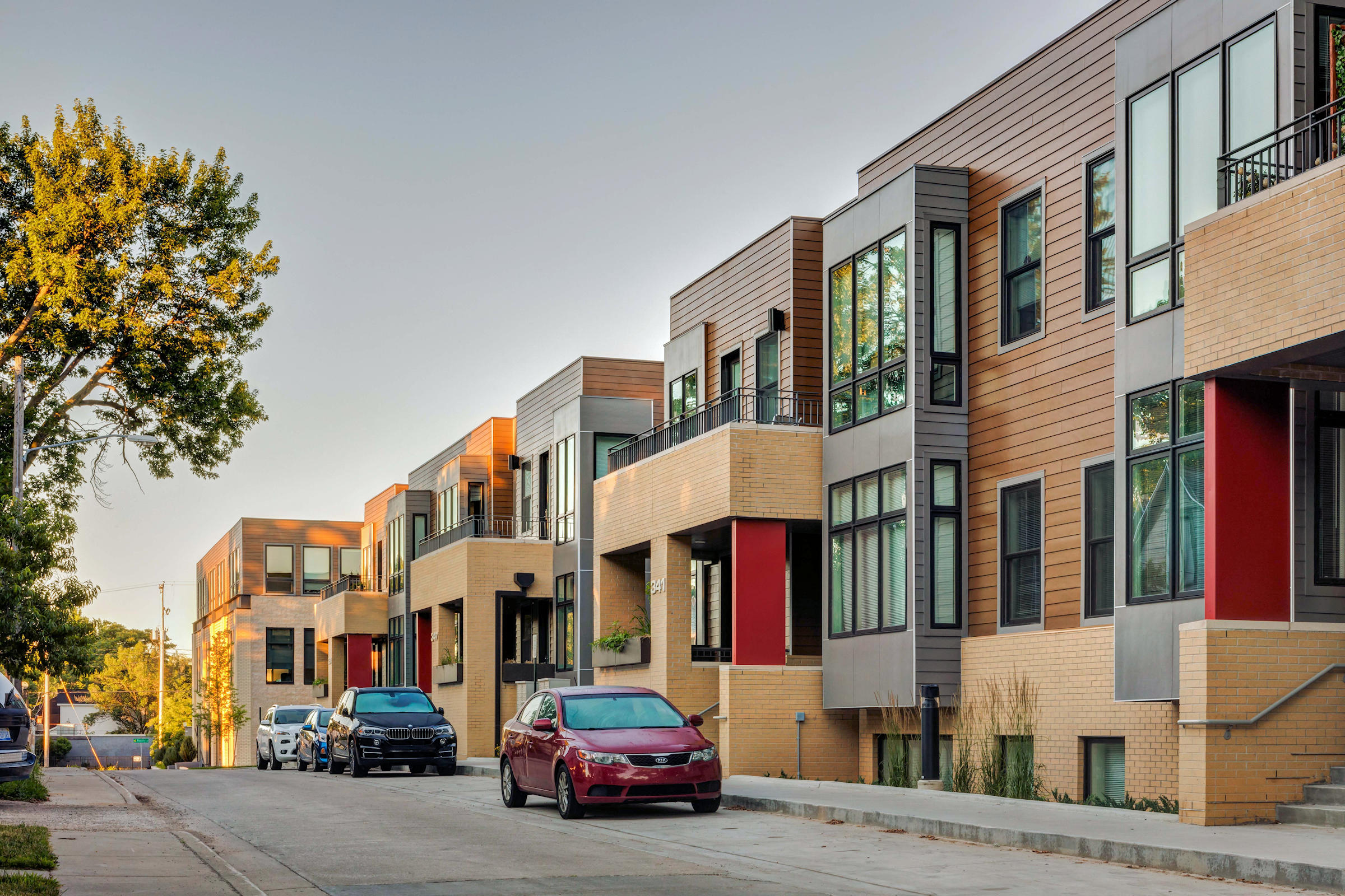 a row of apartment buildings with cars parked in front of them