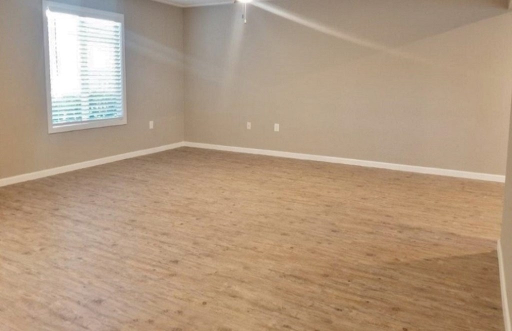 Living room view with well lit window and wood like flooring