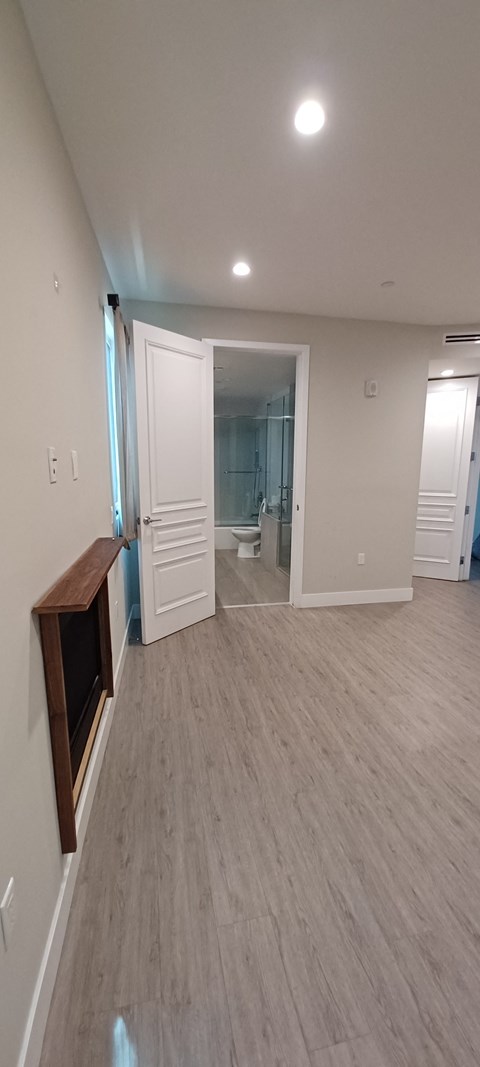 a living room with a tv and a hallway to a bathroom