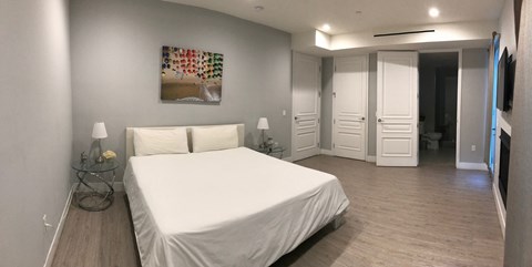 a bedroom with a white bed and a painting on the wall