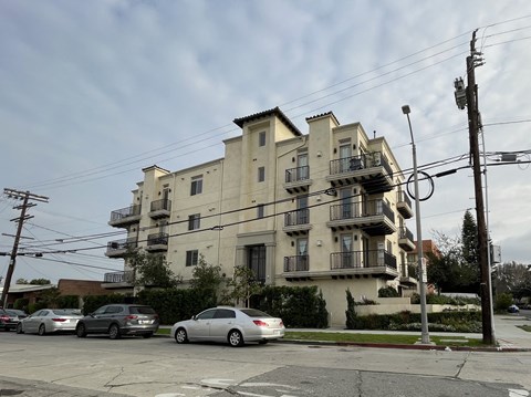 an apartment building on the corner of a street with parked cars