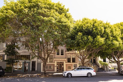 A white car is parked on the street in front of a building.