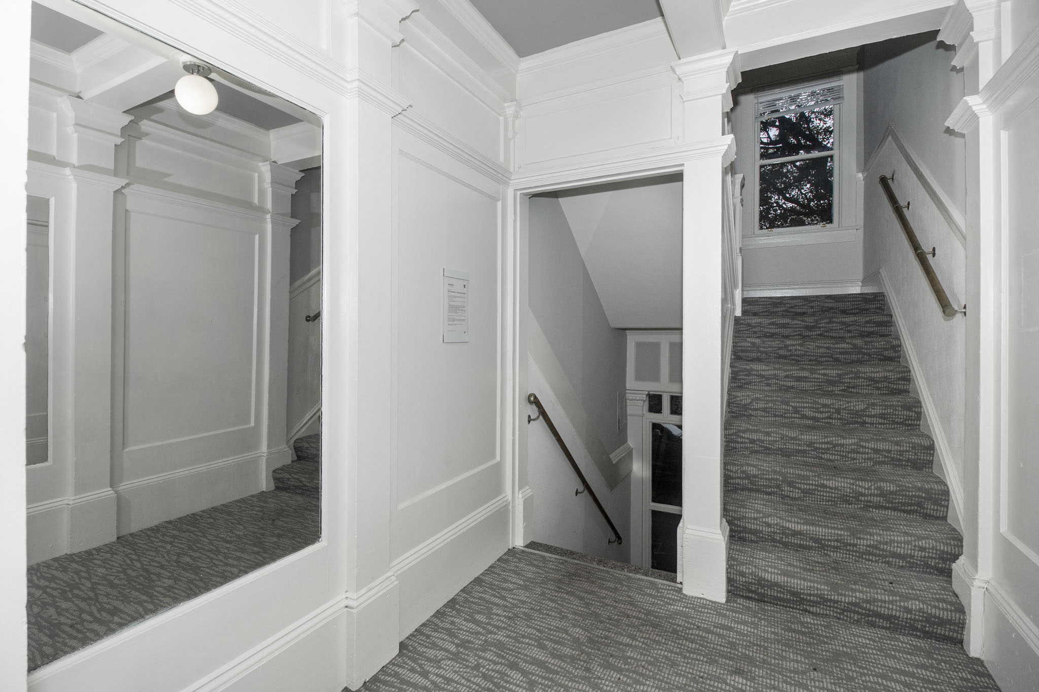 A stairway with a carpeted runner and white walls.