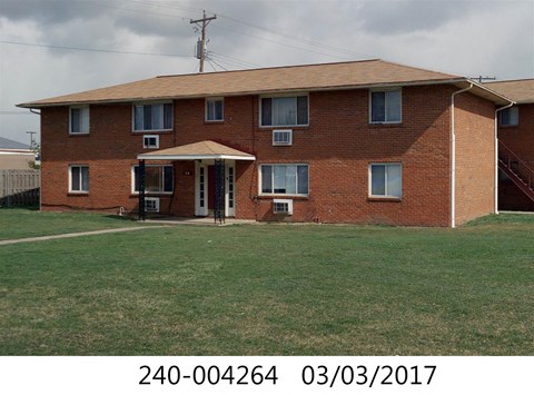 the front of a brick house with a lawn