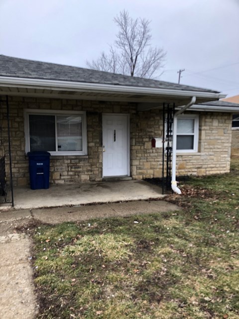 A house with a white door and a blue trash can.
