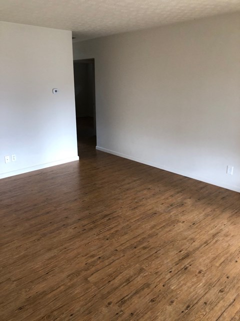 A room with wooden flooring and white walls.