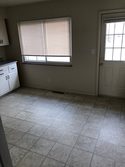 A kitchen with white cabinets and a white door.